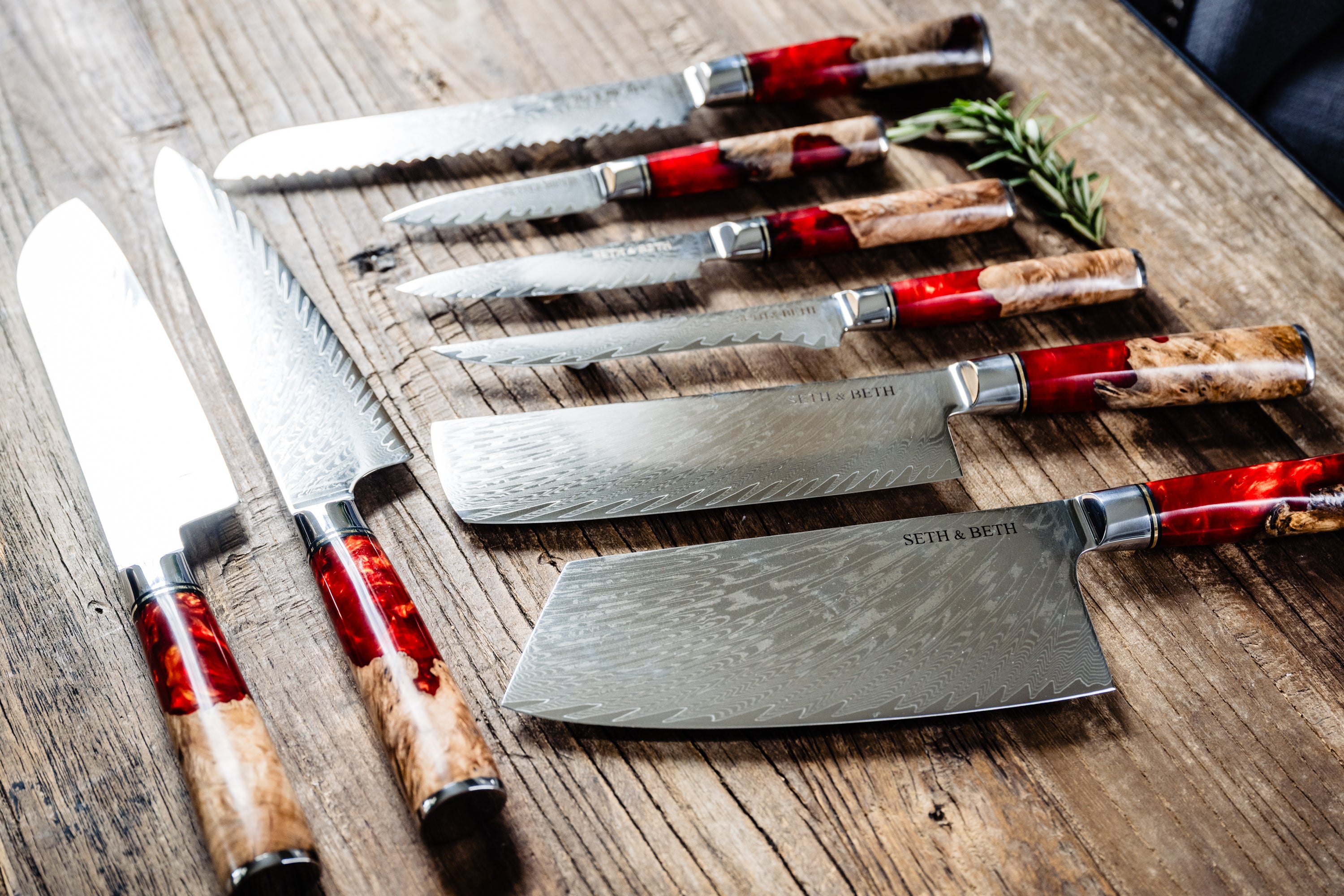 Red burl handle engraved Damascus knife set displayed on wooden surface — Tidal Series